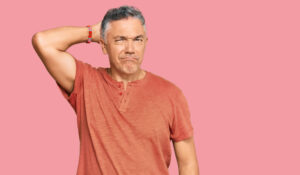 Puzzled man scratching his head on a pink background