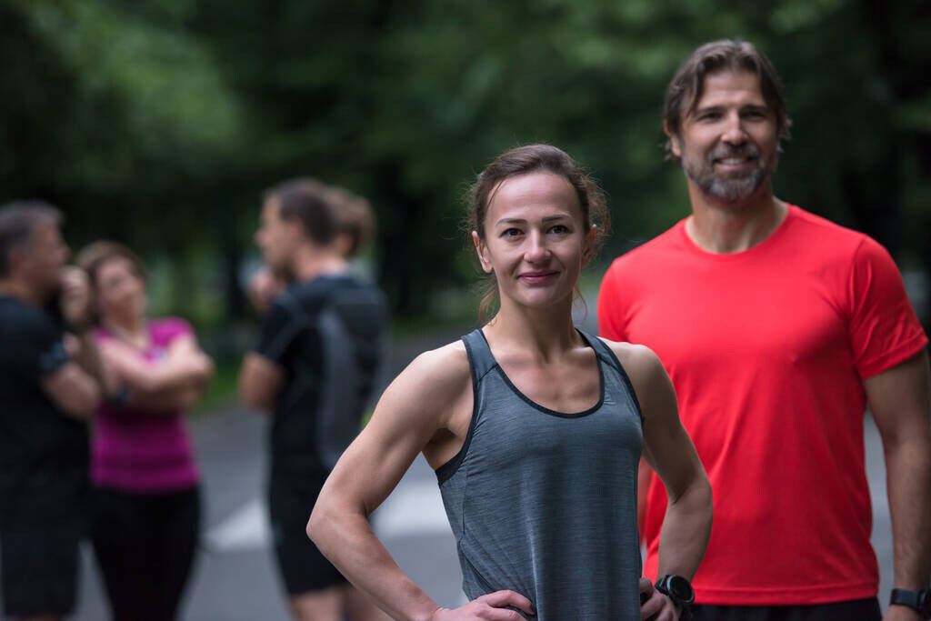 portrait of a healthy jogging couple with the rest of their running team in the background