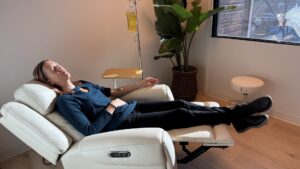 Woman resting in a white recliner while receiving an IV infusion treatment