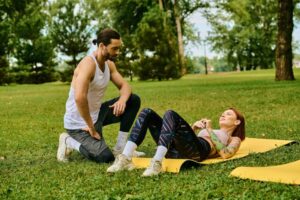 man and woman outside in grass on yoga mat