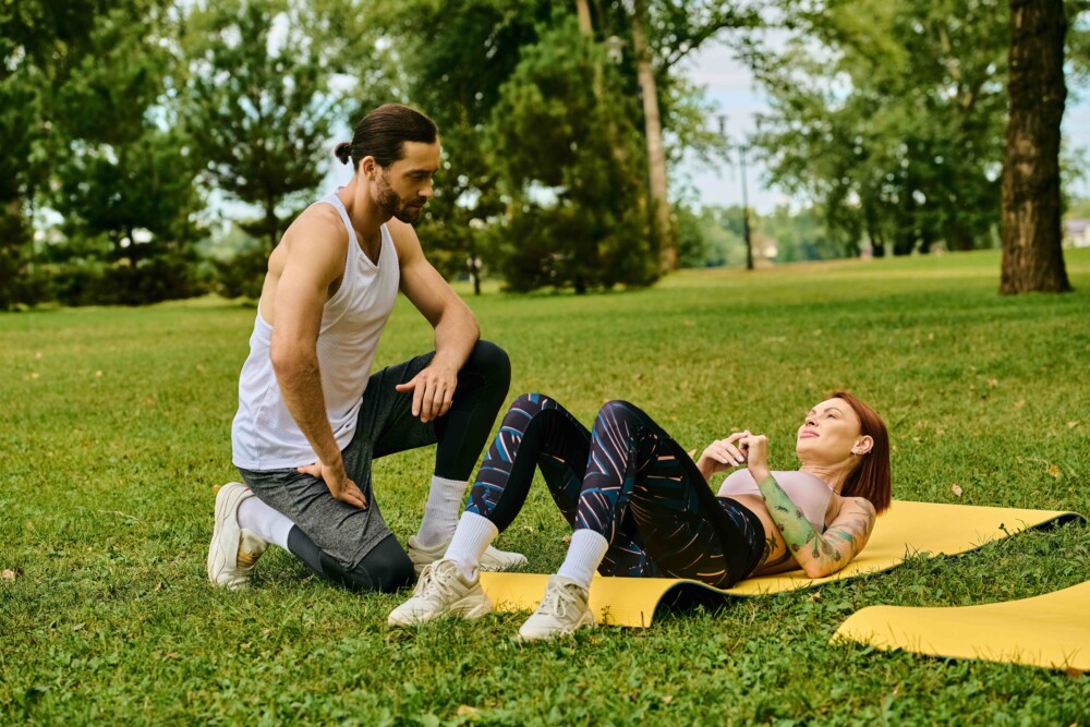 man and woman outside in grass on yoga mat