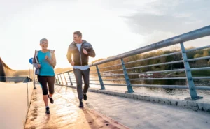 Two adults jogging together along a riverside path at sunrise