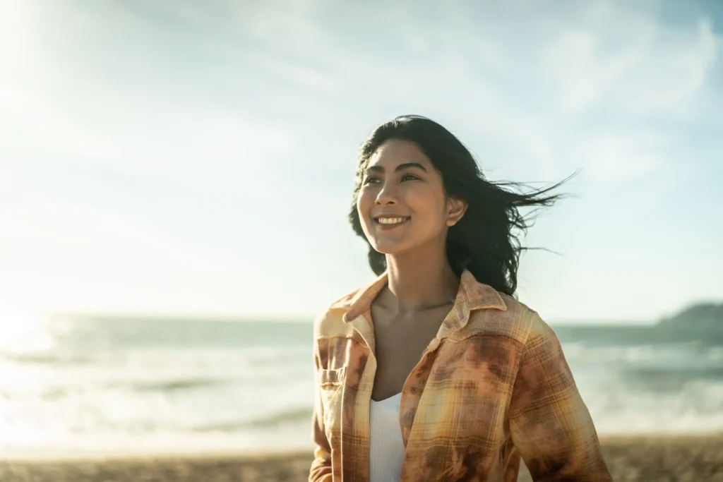 Smiling woman enjoying fresh air while walking along the beach