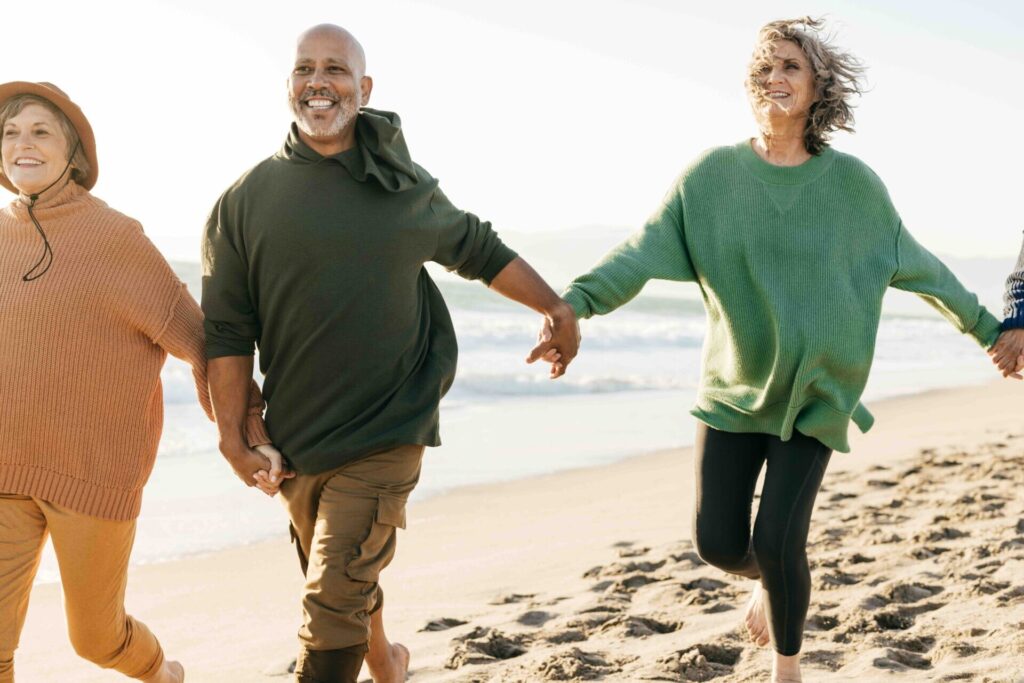 Group of adults holding hands and walking along the beach together on a sunny day