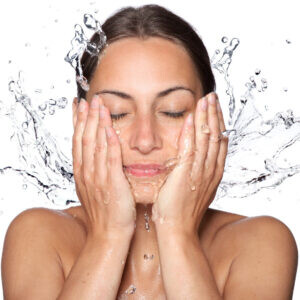 Woman splashing water on her face representing hydration and recovery from the Myer's Cocktail IV at Flow Wellness