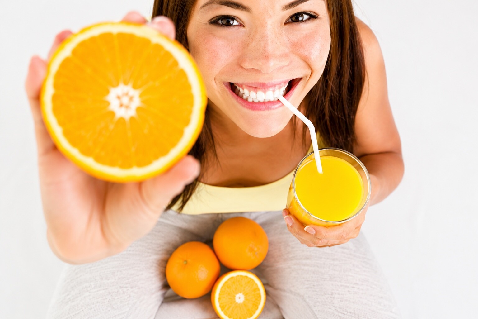 Woman holding fresh oranges representing immune support IV therapy at Flow Wellness