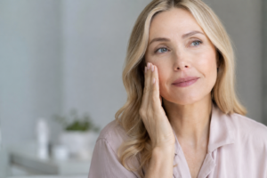Woman in her 40s with healthy glowing skin during perimenopause, gently applying skincare from Flow Wellness in a bright minimalist setting.