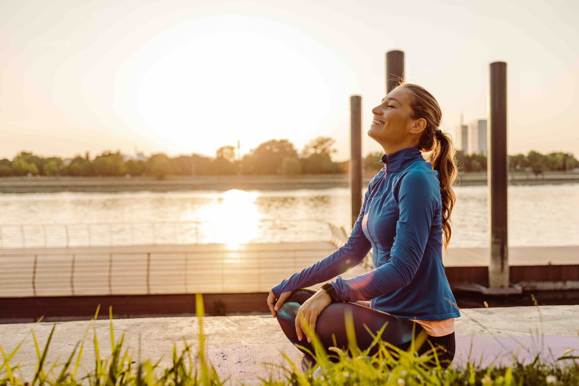 Woman practicing mindful meditation outdoors at sunrise beside the water, seated in a yoga pose with eyes closed and a peaceful expression. The warm morning light and natural setting represent balance, stress relief, healthy aging, and overall wellness. Featured image for Flow Wellness, providing medically guided hormone optimization, bioidentical hormone replacement therapy (BHRT), weight loss, IV therapy, peptides, and wellness care in Oregon and Washington.