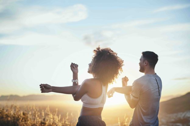 Two people stretching outdoors together at sunrise before exercise